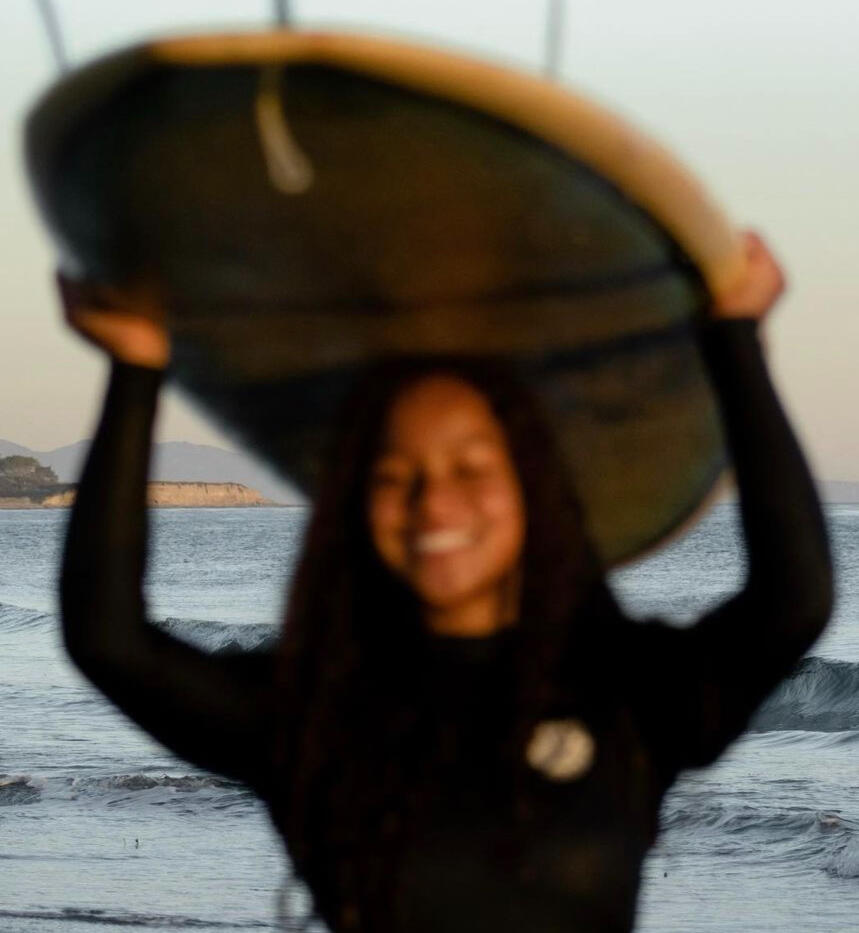 A close up picture of me (Cheyenne Galloway) holding my 9-foot surfboard after having a fun surf sesh.